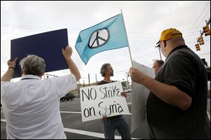 Jeff Klein of West Toledo, center, talks during a rally Wednesday at Secor Road and Central Avenue to show opposition to any U.S. military strike on Syria.