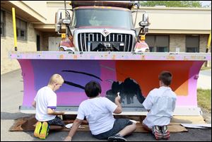 Crim Elementary school students Kaleb Davis, left, 10, David Siegel, center, 10, and Garrett Ford, right, 10, paint the claw on the snow plow blade that they designed. 