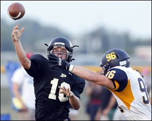 Perrysburg QB Gus Dimmerling throws while under pressure by Whitmer’s Blake Bengela. Dimmerling rushed 26 times for 117 yards and passed for 179 yards.