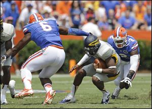 Toledo quarterback Terrance Owens, center, can't find room to run as he is caught between Florida defensive end Dante Fowler Jr. (6) and defensive lineman Dominique Easley (2) in the first half.