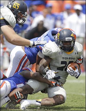 Toledo running back David Fluellen, right, is tackled after a short gain by Florida defensive back Brian Poole, lower left, and linebacker Michael Taylor, center, in the first half.