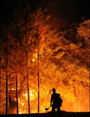 Big Bear firefighter Jon Curtis keeps an eye on the flames of an encroaching 'slop over' fire that jumped Hwy 120 east of Hardin Flat Rd. in the Stanislaus National Forest this week.