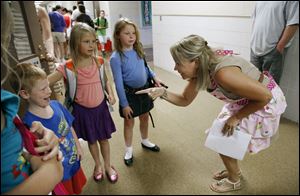 Kim Hohlbein greets her new student Ben Schalow, 7, as his sisters Lily, 7, and Kylie, look on.