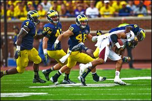 Central Michigan's Winslow Chapman is tackled by Michigan's Channing Stribling as he is chased by a group of Wolverines. Michigan had four sacks in  the game.
