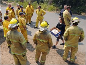 Modesto's Jessy Boonstra, from Ripon Immanuel Christian Reformed Church, carries a box of home baked cookies she brought along with Ripon Fire Chief and San Joaquin County Operational Area Coordinator Dennis Bitters, on a surprise visit to a strike team of San Joaquin County firefighters working along Forest Service road 31 behind Long Barn off of Hwy 108 Wednesday afternoon.