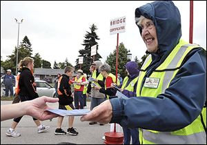 Gloria Reid of Washington, Mich., hands out certificates at the bridge walk. Prizes to to walkers with lucky numbers. 