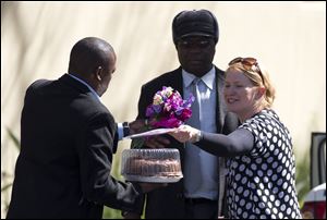 A well-wisher hands flowers and a cake to security guards outside the residence of former South African President Nelson Mandela in Johannesburg.