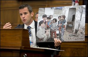 House Foreign Affairs Committee member Rep. Adam Kinzinger, R-Ill. holds up a photograph of Syrian children as he speaks on Capitol Hill in Washington, Wednesday, Sept. 4, 2013, during the committee's hearing on Syria.