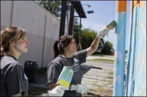 Abby Lewis of Perrysburg, right, paints with Danielle Scott of Maumee as they volunteer with others from MassMutual at the Munchie's Again building.