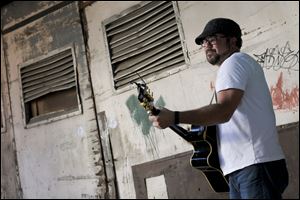 Toledo resident and local musician Jeff Stewart performs in an alley behind the Ye Olde Cock n Bull for a music video Wednesday in downtown Toledo.