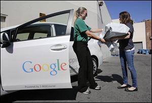 Google Shopping Express driver Ashley Beach, left, picks up packages from Sofe Ring, operations manager, in Palo Alto, Calif. Google has about 50 cars on the streets in an invitation-only experiment with a same-day delivery service.