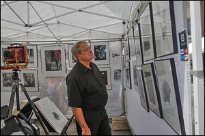 John Csomos of Maumee looks over the large format work of photographer J.D. Nolan at the annual Black Swamp Arts Festival in Bowling Green. The festival offered a mix of artists, from photographers to potters to glassmakers and more.