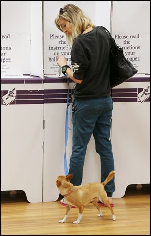 Ainslie Maher keeps an eye on her dog Sanchez as she fills in her ballot today at a polling booth at Bondi Beach in Sydney.