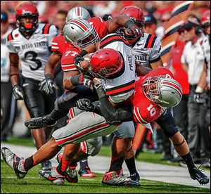 Ohio State defenders Michael Hall, left, and Ryan Shazier, right, bring down San Diego State running back Chase Price during the second quarter Saturday in Columbus. The Buckeyes have won 14 consecutive games.