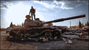 This citizen journalism image provided by the Syrian Revolution against Bashar Assad shows a Free Syrian army fighter standing on a damaged military tank in Zabadani, near Damascus on Sunday.