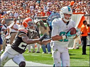 Miami's Brian Hartline, a former Ohio State receiver, catches a 34-yard touchdown pass against Cleveland's Buster Skrine in the third quarter.