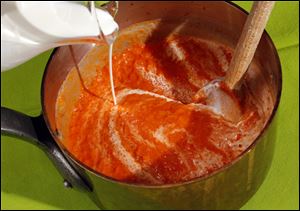Cream is poured into tomato sauce.