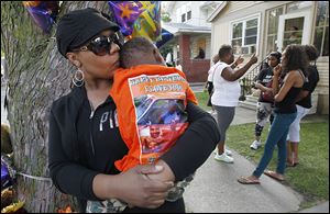 Franshawn Harris kisses her grandson, James Bragg III, outside his house on Cottage Street in Toledo. James lost his dad, James Bragg, to a shooting over the weekend.
