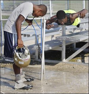 Dink Wyatt, left, and C.J. Chilupe take a water break during football practice at Maumee High School.