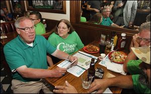 Michael Collins shows supporters, including Carol Leggett, right, early election results at Doc Watson's in Toledo, Ohio.