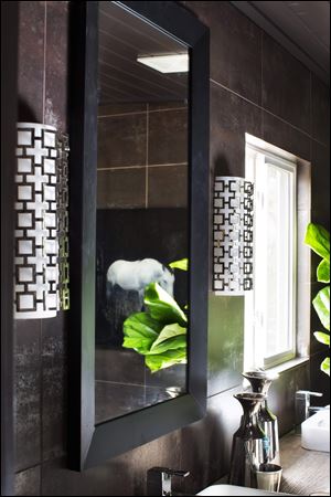 Wall sconces flank a bathroom mirror, adding ample light while also functioning as pieces of decorative art. 