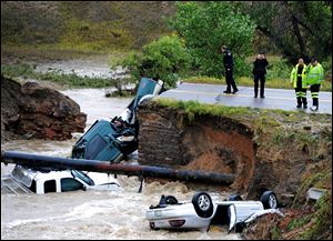 Officials investigate the scene of a road collapse at Highway 287 and Dillon at the Broomfield/Lafayette border, Colo., that sent three vehicles into the water after flash flooding today. The National Weather Service has warned of an 