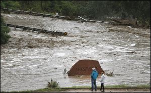 Local residents look over a road washed out by a torrent of water following overnight flash flooding near Left Hand Canyon, south of Lyons, Colo..