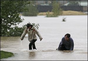 A couple plays in flood water at Utah Park in Aurora, Colo., on Thursday. The park was under water due to flooding. 