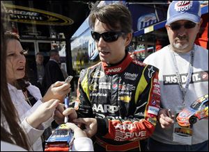 Driver Jeff Gordon signs autographs for fans as he walks to his garage today during practice for Sunday's NASCAR Sprint Cup Series auto race at Chicagoland Speedway in Joliet, Ill.