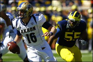 Akron sophomore quarterback Kyle Pohl (16) looks to pass as Michigan senior Jibreel Black (55) runs to attempt a tackle.