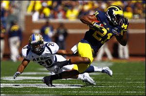 Michigan senior Jeremy Gallon (21) dodges Akron senior Malachi Freeman (20).