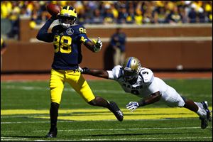 Michigan quarterback Devin Garder goes for a pass as Akron defender C.J. James runs in for the tackle today at Michigan Stadium in Ann Arbor.