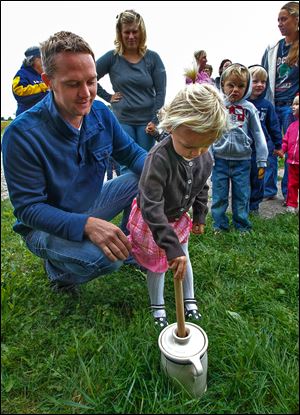Bedford resident Paul Pirrone watches his daughter Tessa, 2, try out the churn at the Johlin Cabin at Pearson Metropark in Oregon. Mr. Pirrone, a Bedford Township trustee, said he wants his children to learn about the past.