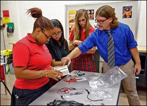 Eric Sieja speaks with, from left, juniors Sam Ferrell, Bonnie Jiang, and Sam Perry, right, while explaining the basics in electrical engineering at Cardinal Stritch High School in Oregon.