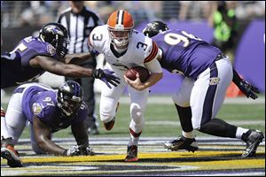 Cleveland Browns quarterback Brandon Weeden scrambles between Baltimore Ravens outside linebacker Terrell Suggs, top left, defensive end Arthur Jones, and defensive end Marcus Spears, right, during the first half today in Baltimore. Weeden left late in the fourth quarter after a possession that produced the Browns’ eighth punt.