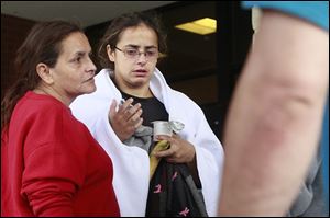 Anna Angel, whose five children and boyfriend were killed in a fire early Sunday morning, is comforted by her mother, Linda Ramirez, left, while leaving Mercy Hospital in Tiffin  on Sunday.