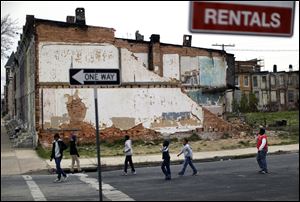 The national poverty rate held steady in 2012 at 15 percent, the Census Bureau reported last week. In this April 4 file photo, children walk past a partially collapsed row house in Baltimore.