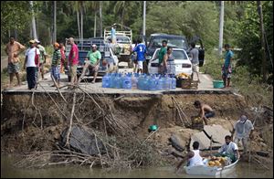 People stand on the edge of a collapsed bridge as they wait to ferry their goods via a boat across the Papagayos River, south of Acapulco.