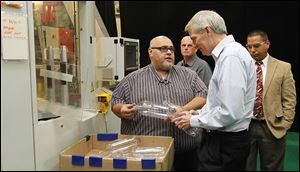 Tom Carros, left, discusses a machine that makes generic 2-liter pop bottles to Sen. Rob Portman during his tour Friday of the Plastic Technologies Inc. plant in Holland.