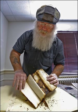 Jesse Mayo examines documents that survived an 1879 fire at the courthouse in Monroe as he does research in the Monroe County Historical Museum. He is to speak at 7 p.m. Oct. 7 at Bedford library.