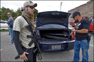 Stephen Recknagel, left, of Toledo holds his AR-15 while friend Steve Stasa, right, from Holland, gets ready with an AK-47 to join Northwest Ohio Carry’s open-carry walk.