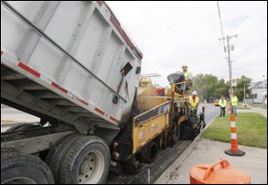 Shannon Scott, of Green Springs, operates the paver, above and left, while co-worker Jamie Bates, of Delta, monitors the asphalt as they work eastward on South Street near Langdon Street.   A crew from the Shelly Company of Findlay, Ohio puts down a leveling layer of asphalt on South Street in Toledo, Ohio on September 23, 2013. The repairing of South Street extends from the Anthony Wayne Trail to the I-75 south onramp.     The Blade/Jetta Fraser
