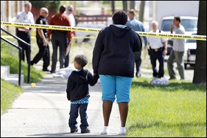Deidra Hopings and her nephew Cross Hoffman, 3, watch as police investigate a shooting at 1520 Elm Street.