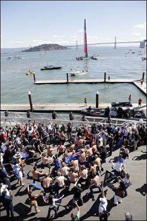 Members of Oracle Team USA board on a dock in preparation for the 19th race of the America's Cup sailing event  against Emirates Team New Zealand, boat seen in the background today in San Francisco.