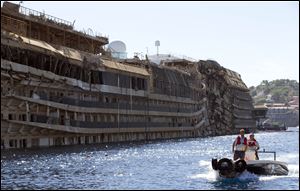 People take a small boat past the damaged side of he Costa Concordia  on the Tuscan Island of Giglio Sept. 18. The capsized ship was pulled upright in an operation the day before.