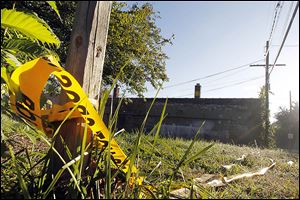 Remnants of crime scene tape mark the location in an alley in the 1200 block of Woodstock Avenue near Dorr Street where Shaun Flowers, 22, was shot to death on Wednesday. 