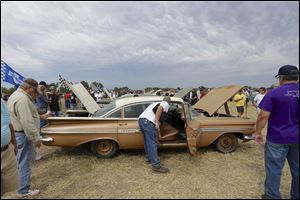 Car buffs survey a 1959 Chevrolet Impala, foreground, and other Chevrolet vehicles.