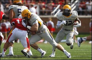 Toledo's David Fluellen (right) runs the ball up field past Ball State Universit.