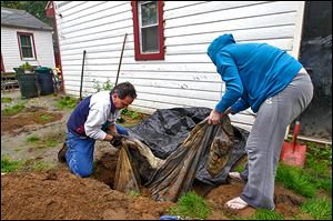 Volunteers John Gibbs and Carissa Curry remove remains from the backyard of a Luann Avenue home. The remains are suspected to be those of a missing dog that was linked to a New York murder.