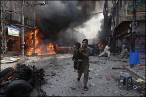 Pakistani men rush away from the site of a blast shortly after a car explosion today in Peshawar, Pakistan.